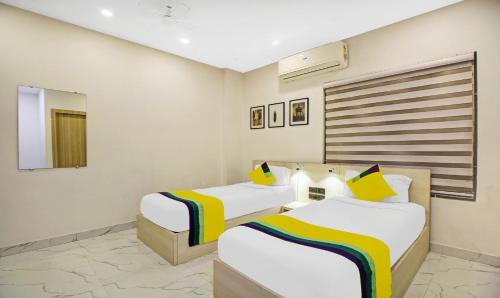 Una habitación de hotel con dos camas y un espejo. en Itsy Hotels Transit Express Near Sealdah Station, en Calcuta