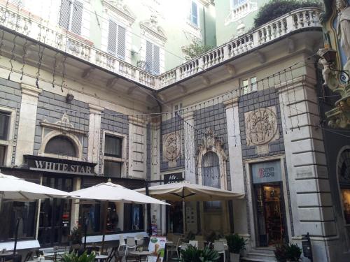 um edifício com mesas e guarda-chuvas à sua frente em Appartamento Piazzetta La Maddalena em Savona