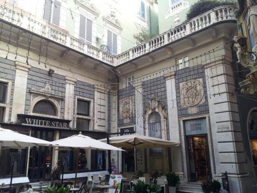 a building with tables and umbrellas in front of it at Appartamento Piazzetta La Maddalena in Savona