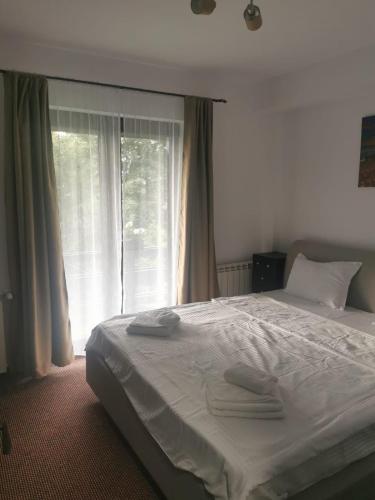 a bedroom with a white bed with a window at Belvedere Resort Moieciu in Moieciu de Jos