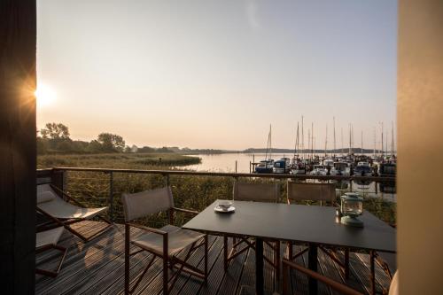 a table and chairs on a balcony with a marina at Im-Jaich Naturoase Gustow in Gustow