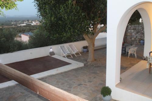 a patio with a table and chairs and a tree at A Crystal Clear House in Pyrgos, Heraklion Crete in Pírgos