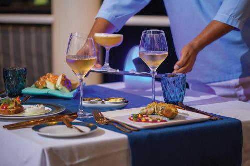 a table with two glasses of wine and food on it at VARU by Atmosphere - Premium All Inclusive with Free Transfers in North Male Atoll