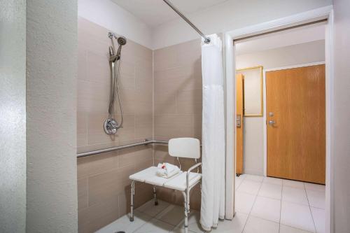 a shower with a white chair in a bathroom at Microtel Inn & Suites by Wyndham Southern Pines Pinehurst in Southern Pines