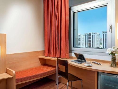 um quarto com uma secretária com um computador portátil e uma janela em ibis Adana em Adana