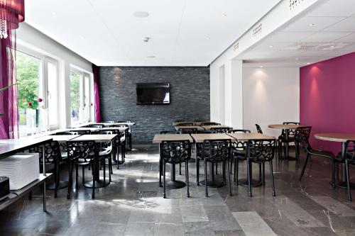 a restaurant with tables and chairs and a wall with a tv at Hotel Allén - Sure Hotel by Best Western Allen in Gothenburg
