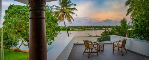 a balcony with two chairs and a view of a river at The Ambassador's Residence Kochi - a VKation Experience in Cochin