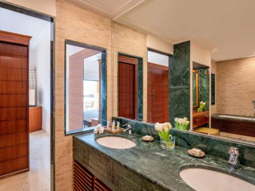 a bathroom with two sinks and a large mirror at Mövenpick Resort & Spa Dead Sea in Sowayma