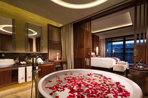un bagno con vasca riempita di fiori rossi di Angsana Xi'an Lintong a Lintong