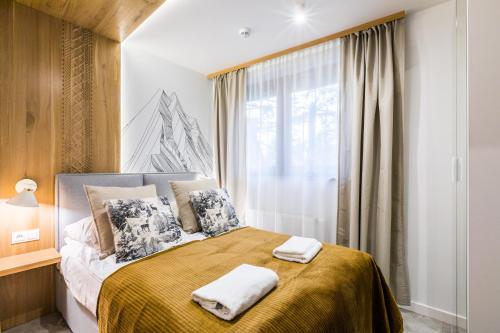 a bedroom with a bed with two towels on it at Apartament Atena in Zakopane