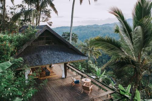 a house in the jungle with a deck and palm trees at Buahan, a Banyan Tree Escape in Payangan