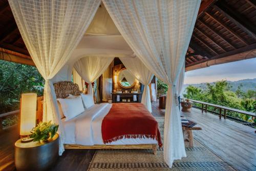 a bedroom with a large bed on a deck at Buahan, a Banyan Tree Escape in Payangan