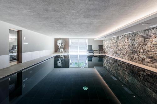 baño con pared de piedra y piscina en Hotel Christof en Monguelfo