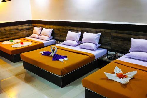 a room with three beds with orange sheets at EliteHotels and Resorts Pvt Ltd in Alibaug