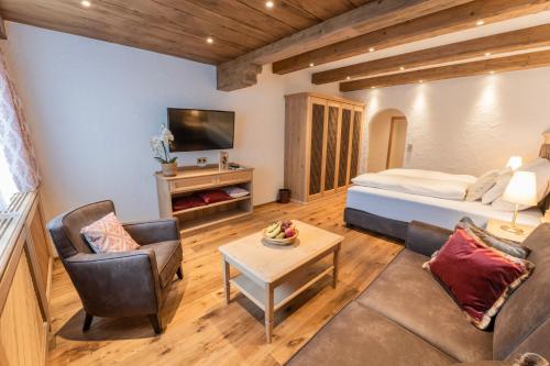 een woonkamer met een bed, een bank en een tafel bij Hotel Ulli in Zürs am Arlberg