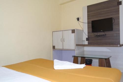 a room with a bed with a tv and a table at Hotel Mukesh Residency in Pune