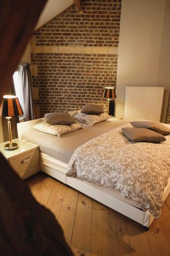 two beds in a bedroom with a brick wall at In De Witte Engel in Lanaken