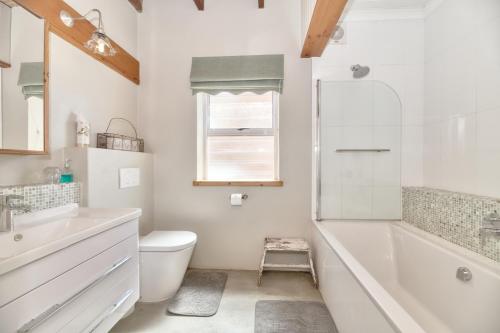 a bathroom with a tub and a toilet and a sink at Colours of the Sea Apartment in Struisbaai