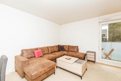 a living room with a brown couch and a table at Bright 68 m2 apartment near the Stade de France in Aubervilliers