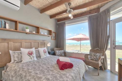 a bedroom with a bed with a view of the beach at Colours of the Sea Apartment in Struisbaai