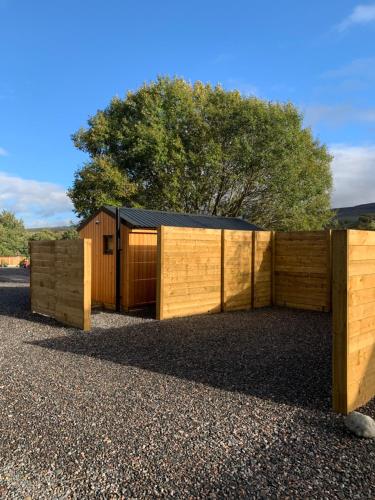 a wooden fence with a building behind it at River Huts with Private Hot Tubs in Inverness