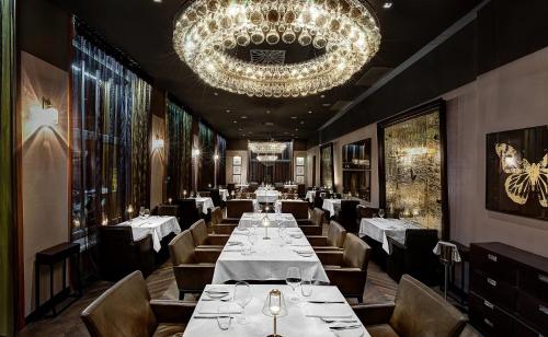 a dining room with tables and chairs and a chandelier at The Emblem Prague Hotel - Preferred Hotels & Resorts in Prague