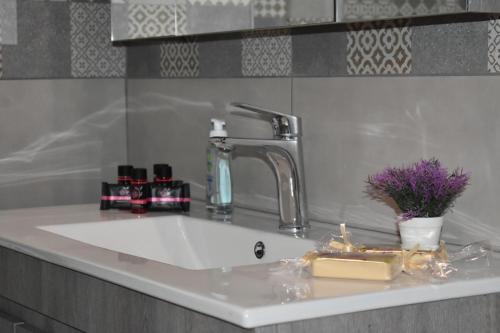 a bathroom sink with a faucet and cosmetics on it at Domenica Studios 2 in Thessaloniki
