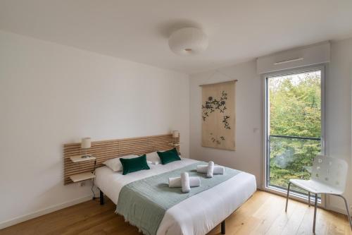 a white bedroom with a large bed and a window at Le Bienveillant - T3 proche Jardin des Plantes in Nantes