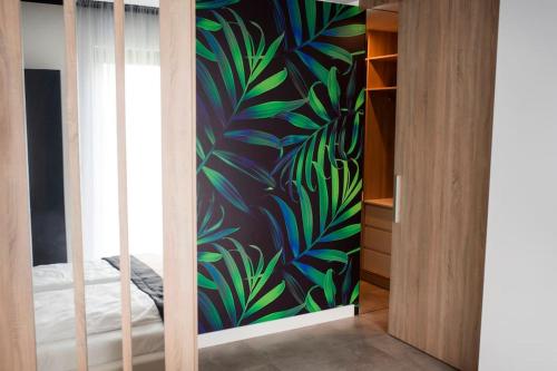 Un dormitorio con una pared con un mural de plantas en Apartament Południowy W80, en Żory