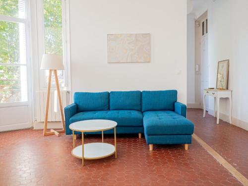 a living room with a blue couch and a table at Le CosyChic - Appartement élégant en centre ville in Orange