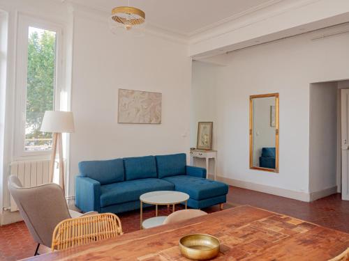 a living room with a blue couch and a table at Le CosyChic - Appartement élégant en centre ville in Orange