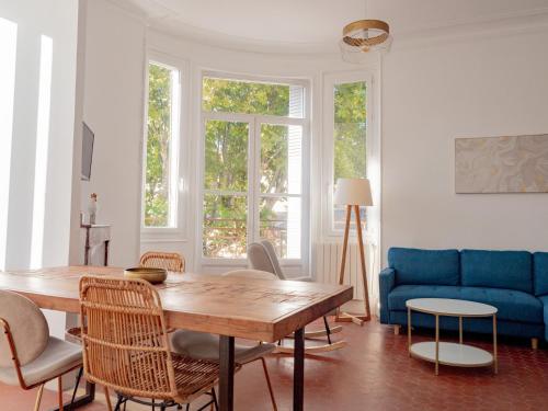 un salon avec une table et un canapé bleu dans l'établissement Le CosyChic - Appartement élégant en centre ville, à Orange