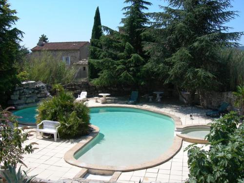 - une grande piscine dans une cour avec une terrasse dans l'établissement Mas du Garidel l Appartements avec piscine privée proche Ardèche à Saint Julien de Peyrolas, à Saint-Julien-de-Peyrolas