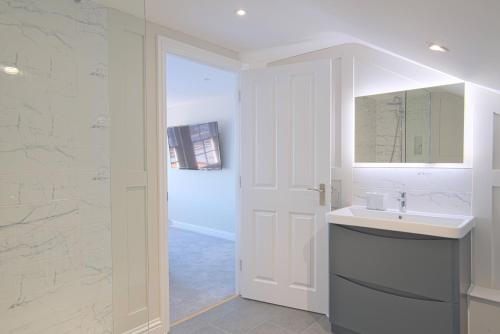 Harper Luxe Serviced Apartments Dunstable في دانستابل: حمام أبيض مع حوض ومرآة