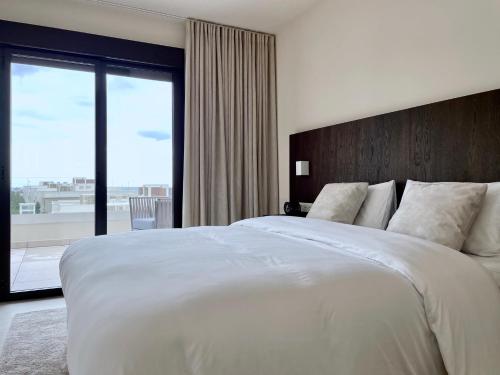 una camera da letto con un grande letto bianco con una grande finestra di Luxury apartment Vida Feliz with sea view 5 min walk to the beach in Jardinana Lotus La Cala de Mijas, Malaga a Mijas Costa