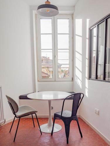 une table et des chaises dans une pièce avec une fenêtre dans l'établissement Le Loft - Appartement moderne en centre ville, à Orange