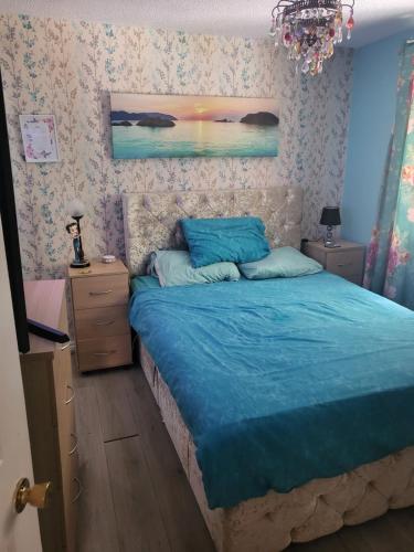 una camera da letto con un letto con lenzuola blu e un lampadario a braccio di Craven Cottage a Knowsley