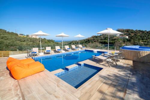 a swimming pool with an orange couch and chairs and umbrellas at Etesians Villa, an essence of timeless beauty, By ThinkVilla in  Episkopi (Chania)