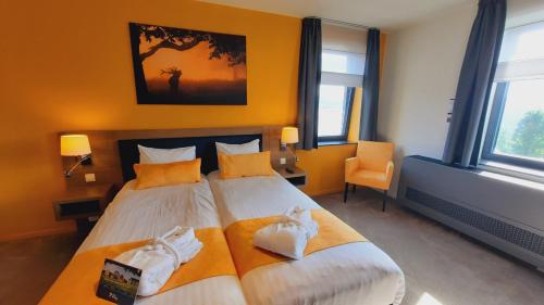 a bedroom with a large bed with orange walls and windows at Azur en Ardenne in Durbuy