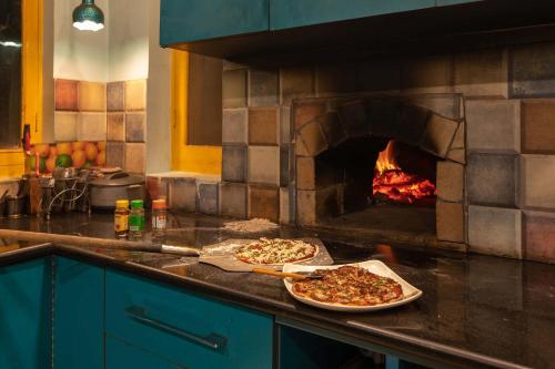 two pizzas sitting on a counter next to an oven at StayVista at Spirits Unplugged with Outdoor Pool - Karyali in Nāldera