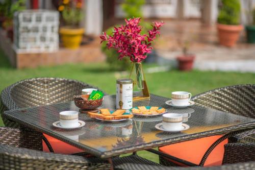 a table with a vase of flowers and coffee cups at StayVista at Spirits Unplugged with Outdoor Pool - Karyali in Nāldera