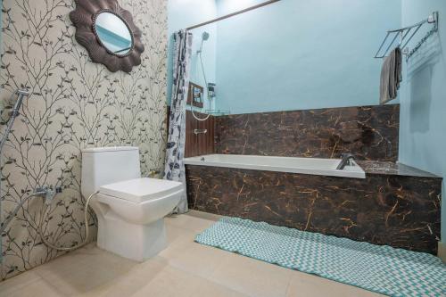 a bathroom with a toilet and a tub and a sink at StayVista at Spirits Unplugged with Outdoor Pool - Karyali in Nāldera