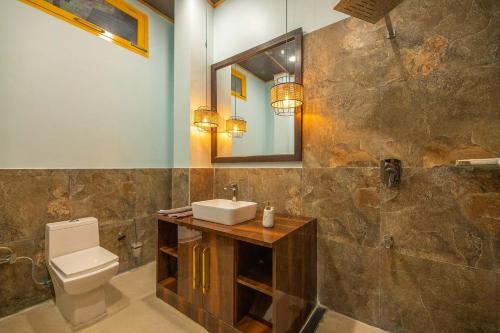 a bathroom with a sink and a toilet and a mirror at StayVista at Spirits Unplugged with Outdoor Pool - Karyali in Nāldera