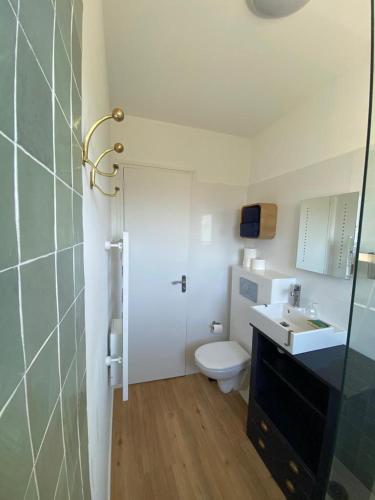 une salle de bain avec des toilettes blanches et un lavabo dans l'établissement Les Pins Penchés, à Villers-sur-Mer