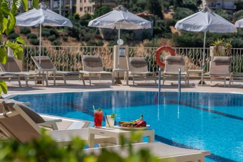 a swimming pool with chairs and a table with drinks at Lofos Apartments in Hersonissos