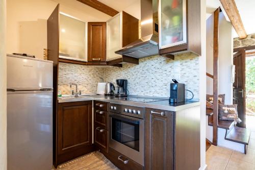a kitchen with stainless steel appliances and wooden cabinets at Angel House Greystone Villa Polydrossos in Polydrossos