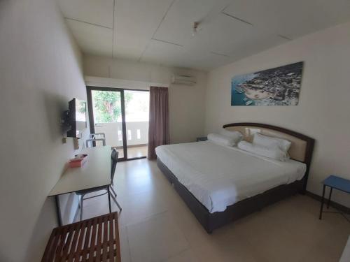 1 dormitorio con cama, escritorio y ventana en Hotel Larensia, en Labuan Bajo