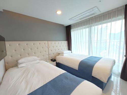 two beds in a hotel room with a window at Hotel STAYON in Geoje 