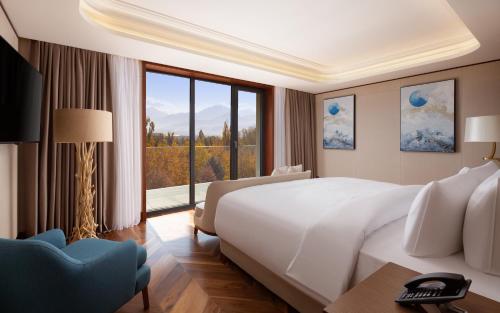 a bedroom with a large bed and a large window at Swissôtel Wellness Resort Alatau Almaty in Almaty