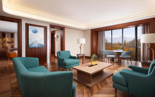 a living room with blue chairs and a table at Swissôtel Wellness Resort Alatau Almaty in Almaty